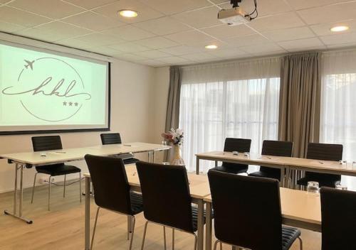 a conference room with tables and chairs and a screen at Brit Hotel Ker Lann Aeroport - Parc Expo in Bruz