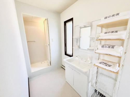 a white bathroom with a sink and a mirror at 宿の夜夜 広々一棟貸し駐車場2台 浴室2箇所 大家族グループ旅行に最適 静かな環境 in Omihachiman