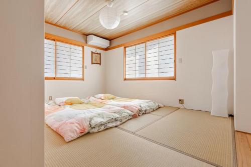 a bedroom with a bed in a room with windows at 宿の夜夜 広々一棟貸し駐車場2台 浴室2箇所 大家族グループ旅行に最適 静かな環境 in Omihachiman