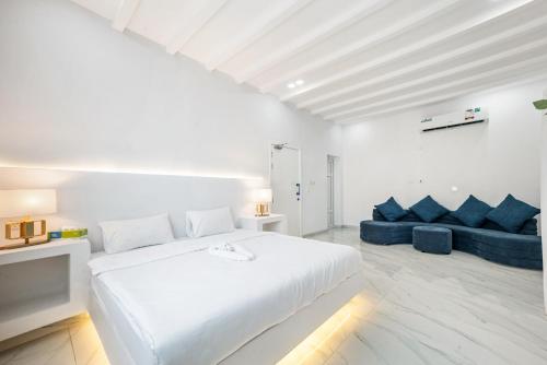 a white bedroom with a bed and a blue couch at Dreams Gate Villa Resthouse 4 in Umm Şalāl ‘Alī