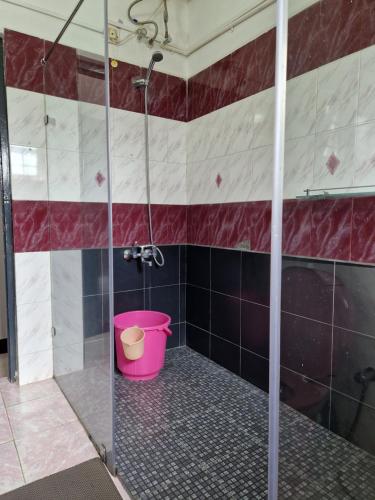a bathroom with a shower with a pink bucket at Narmada Holiday Home in Ooty