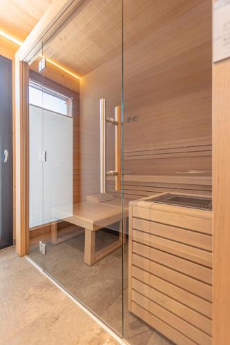 a sauna with a bench and a glass wall at Bergresort Hauser Kaibling by ALPS RESORTS in Haus im Ennstal