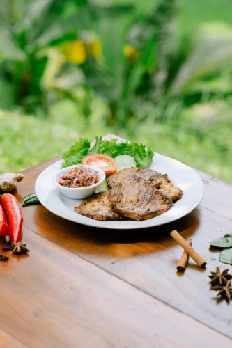 a plate of food with meat and vegetables on a table at Saridevi Ecolodge in Jatiluwih