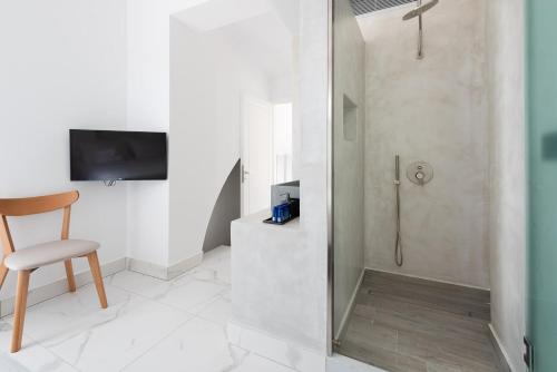 a bathroom with a shower and a chair and a television at Karat Suites in Vóthon