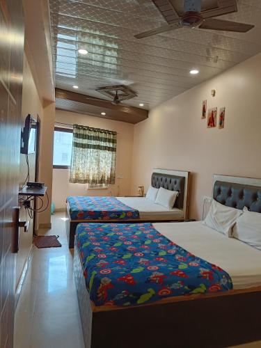a bedroom with two beds and a flat screen tv at Pragya international in Varanasi