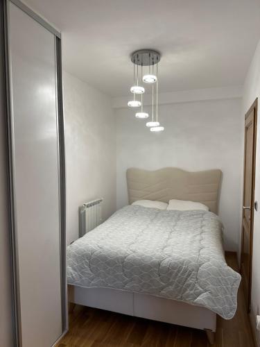 biała sypialnia z łóżkiem i żyrandolem w obiekcie Sarajevo Boulevard w Sarajewie