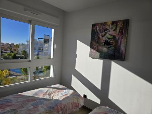 a bedroom with a bed and two windows at Bali Apartment Punta Prima in Torrevieja