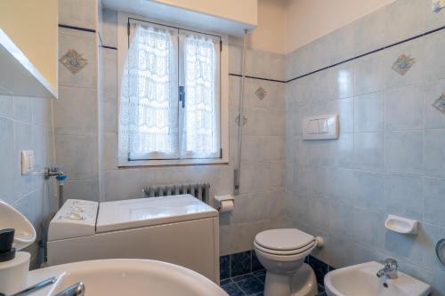 a bathroom with a toilet and a sink and a window at Garden - residence in the center of Barzio in Barzio
