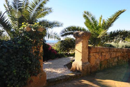 a garden with a stone wall and palm trees at Villa La Lumia B&B Suites & Apartments in Agrigento