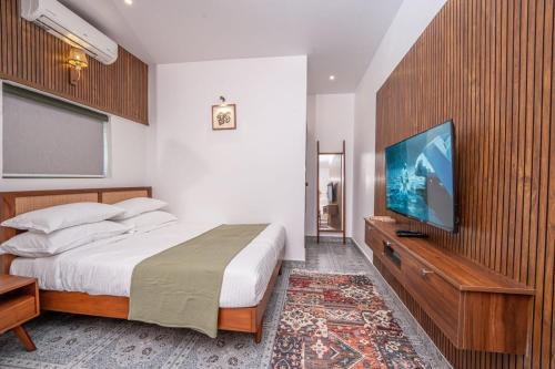 a bedroom with a large bed and a flat screen tv at EarthLoft Villa in Kalpetta