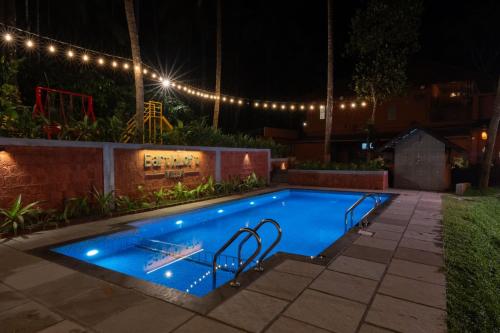 a swimming pool with lights in a backyard at night at EarthLoft Villa in Kalpetta