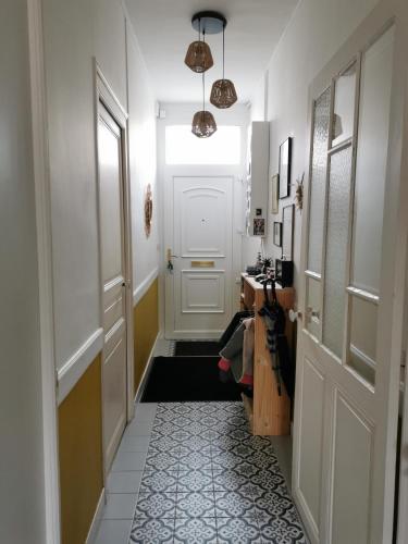 un couloir avec une porte blanche et du carrelage. dans l'établissement Maison de ville - Proche gare, au Mans