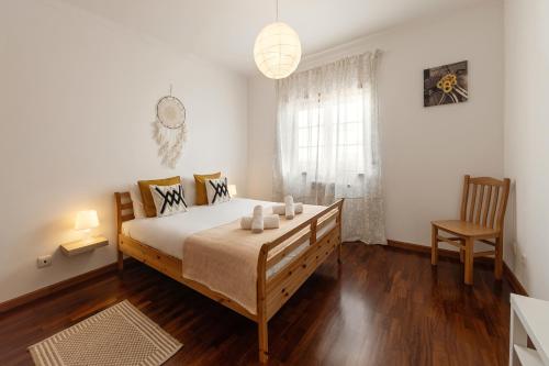 a bedroom with a bed and a chair and a window at Casa da Barragem in Atouguia da Baleia