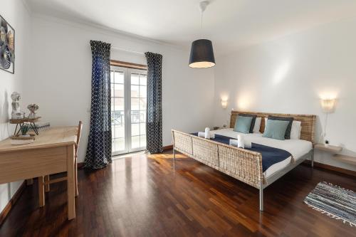 a bedroom with a bed and a desk and a window at Casa da Barragem in Atouguia da Baleia