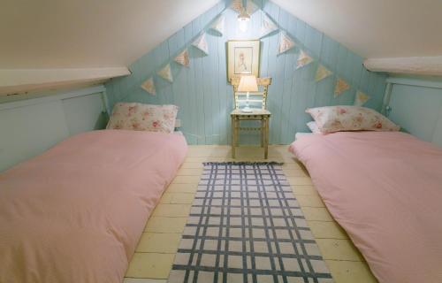 two beds in a room with blue walls at Pentir in Penmon
