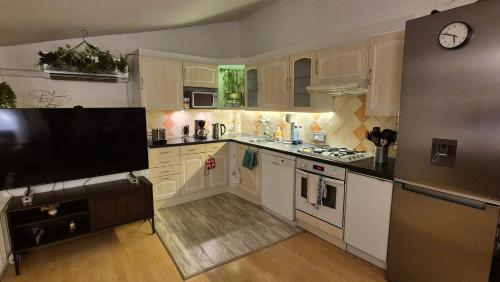 une cuisine avec des armoires blanches et une télévision à écran plat dans l'établissement Maison de village en Provence verte, à Sainte-Anastasie-sur-Issole