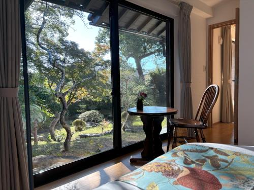 a room with a large window with a table and chairs at Cottage LALA GARDEN in Kumamoto