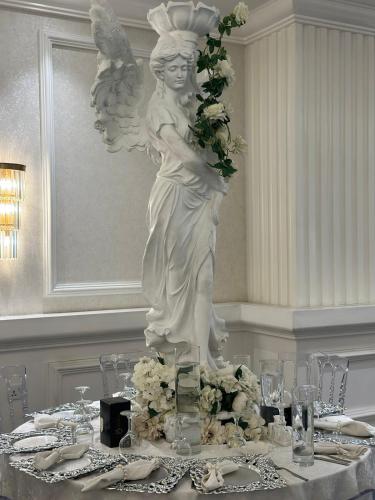 a statue of a woman holding a bouquet on a table at Hyksos Hotel in Erbil