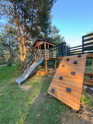 a wooden playground with a slide and a gazebo at Dom Na Brzegu Ciszy in Pasym