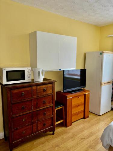 a kitchen with a microwave and a dresser with a tv at Laburnum Guest House in Colnbrook