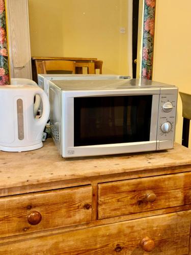 a microwave sitting on top of a wooden dresser at Laburnum Guest House in Colnbrook