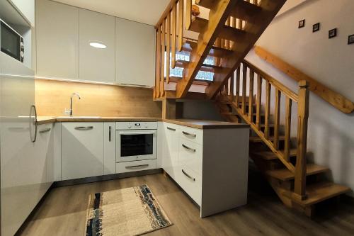 a kitchen with white cabinets and a wooden staircase at Chalupa Evka in Terchová