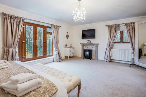 a large bedroom with a bed and a fireplace at Luxury6BedHouse-HotTub-GamesRoom-Amar Luxury Stays in Poole