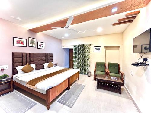 1 dormitorio con 1 cama grande y 2 sillas verdes en Tiger Heaven Resort, en Tāla