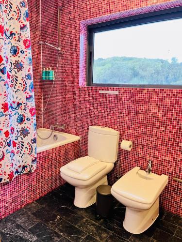 a bathroom with a toilet and a sink and a window at São Vicente Lodge - Panoramic Retreat in Capelas