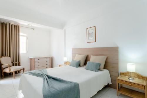 a white bedroom with a large bed and a chair at Atlantida by Garvetur in Quarteira