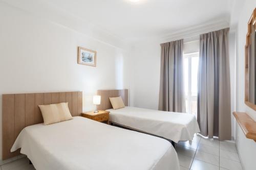 a hotel room with two beds and a window at Atlantida by Garvetur in Quarteira