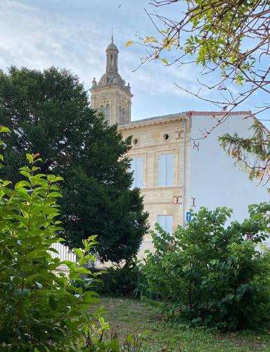 un bâtiment avec une tour d'horloge au sommet dans l'établissement Maison au cœur des vignes, à Saint-Estèphe