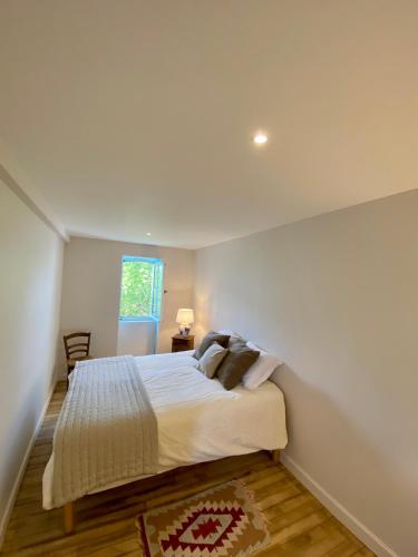 une chambre avec un grand lit blanc avec une fenêtre dans l'établissement Maison au cœur des vignes, à Saint-Estèphe