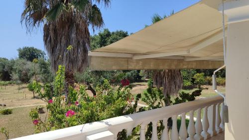 a porch with a white fence and a white umbrella at Private holiday villa close by to Halikunas beach and Korission lagoon in Halikounas