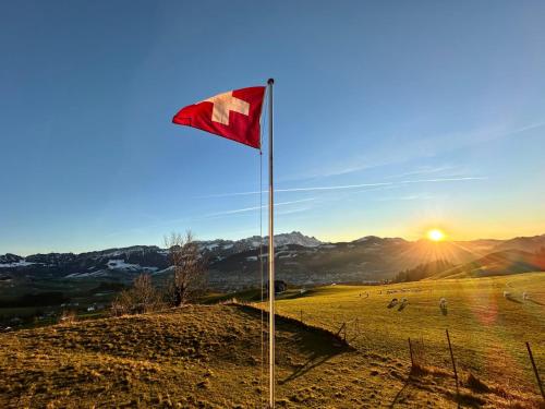 a flag on a hill with the sun in a field at Ferienhaus Alpsteinsicht in Appenzell