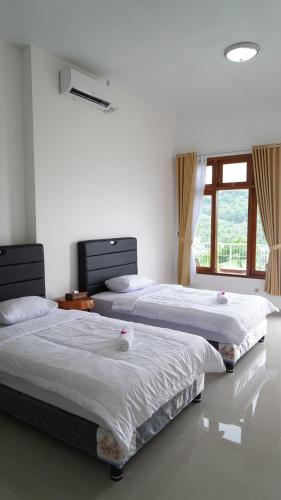 two beds in a bedroom with a window at Arirang Sea View Homestay in Senggigi 