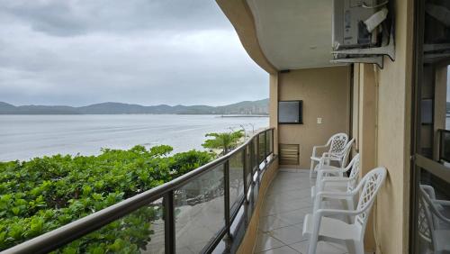 a balcony with chairs and a view of the ocean at Lindo Apto Itapema Meia Praia Frente ao Mar, 6 pessoas, alto padrão in Itapema