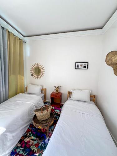 two twin beds in a room with a table at Locals Taghazout surfcamp in Taghazout