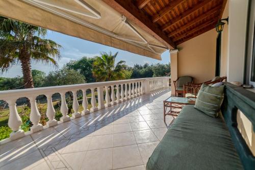 a balcony with a view of a palm tree at Private holiday villa close by to Halikunas beach and Korission lagoon in Halikounas