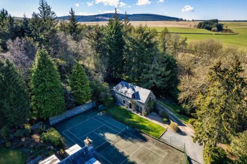 Black Barony Home Farm Cottage في إيدلستون: اطلالة جوية على منزل مع ملعب تنس
