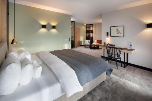a bedroom with a large bed and a desk at Wellness & Genuss Resort - Engel Obertal in Baiersbronn