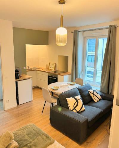 un salon avec un canapé et une table dans l'établissement Appartement Résidence Lenoir - Centre REIMS, à Reims