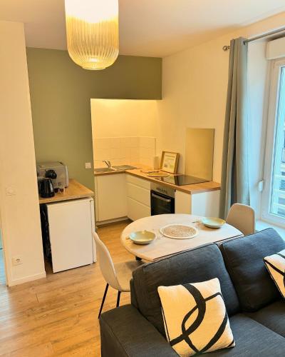 un salon avec un canapé et une table et une cuisine dans l'établissement Appartement Résidence Lenoir - Centre REIMS, à Reims