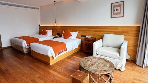a hotel room with two beds and a chair at the Wild Luxury Holiday Inn in Xingping