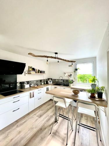 une cuisine avec des armoires blanches et une table en bois dans l'établissement Appartement T3 - forêt & plage, à Anglet
