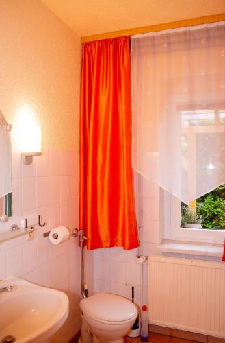 an orange curtain in a bathroom with a toilet and a window at -Waldhaus-Fewo 3 in Mirow