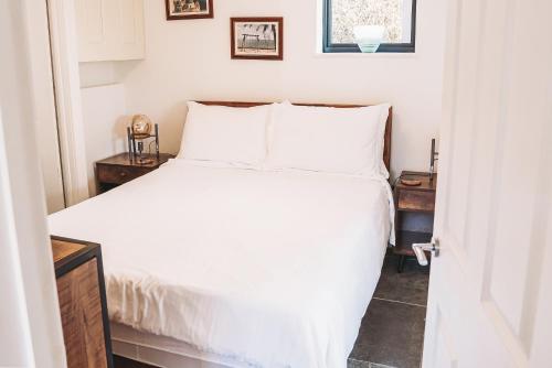 a bedroom with a bed with white sheets and pillows at Cottage with Hot Tub - near Cheltenham and Tewkesbury in Cheltenham