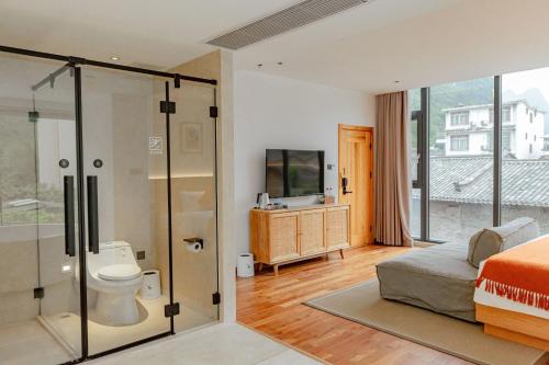 a bedroom with a bathroom with a toilet and a tv at the Wild Luxury Holiday Inn in Xingping
