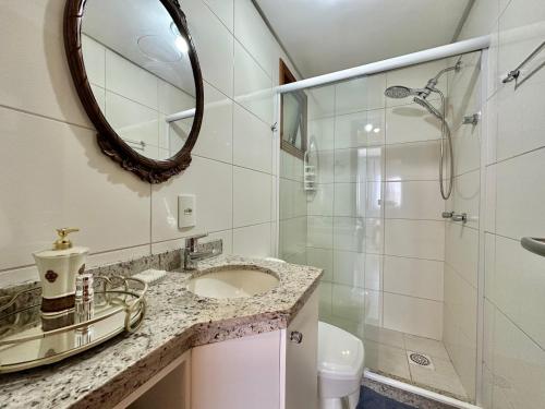 a bathroom with a sink and a shower and a mirror at Apartamento com vista para o mar in Capão da Canoa