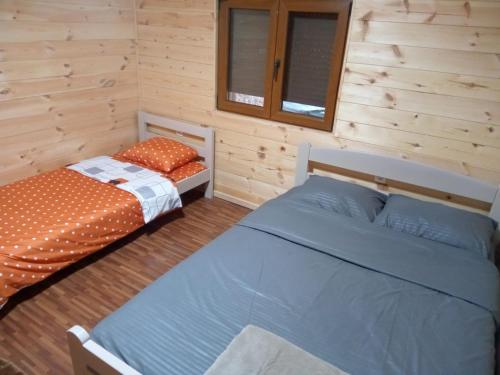 two beds in a room with wooden walls at House under peaks in Kozarica